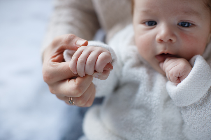 The kid holds his mother firmly by the finger