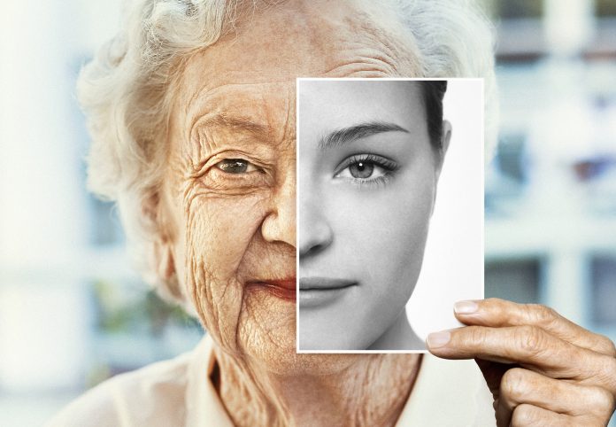 Portrait of woman holding black and white younger photo of herself