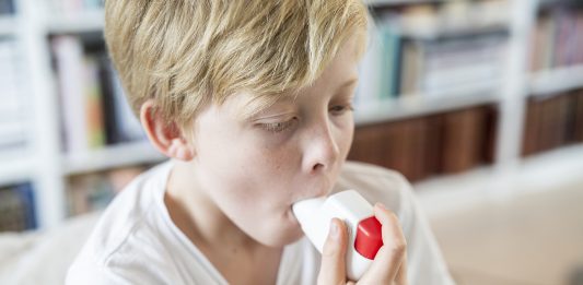 Boy using inhaler to illustrate allergic diseases of childhood