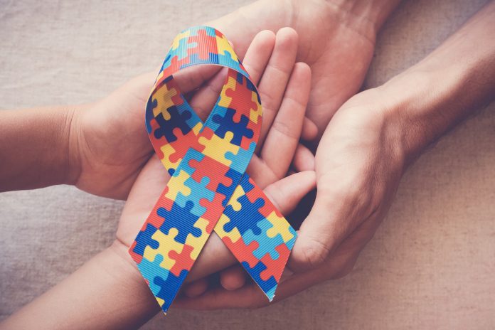 Hands holding puzzle ribbon for autism awareness