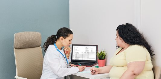 Nutritionist calculating body mass index of woman for obesity treatment in a clinic room. Mutations in the TRPC5 gene can cause obesity and postpartum depression.