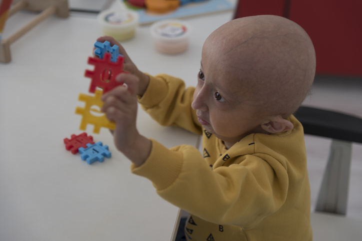 A child with the premature aging disease progeria playing with a toy on a table